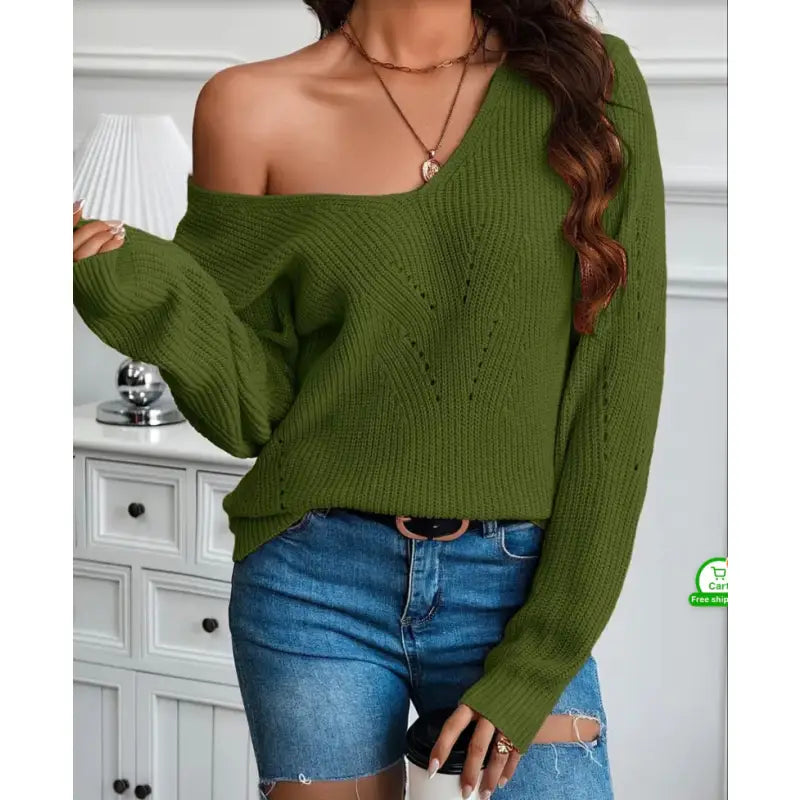 Person wearing a green off-shoulder sweater and blue jeans indoors.