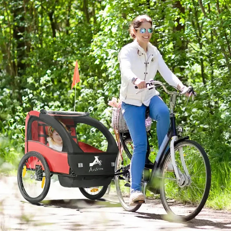 Woman riding a bicycle with a child trailer.