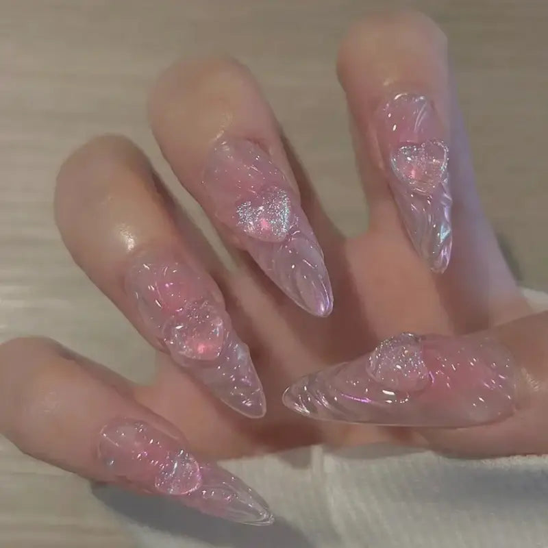 Pointed, translucent pink nails with heart embellishments.