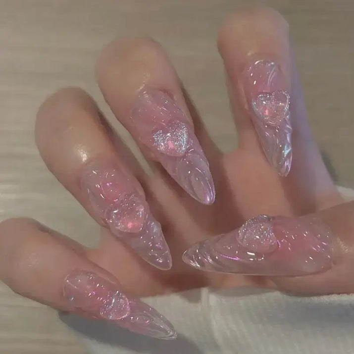 Pointed, translucent pink nails with heart embellishments.
