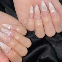 Almond-shaped nails with heart and pearl embellishments.
