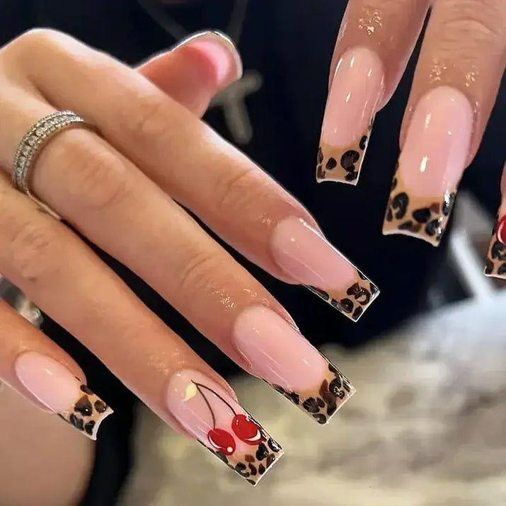 Long, pink nails with leopard print tips and cherry design.