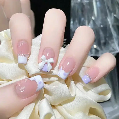 Fingernails with French tips and embellishments.