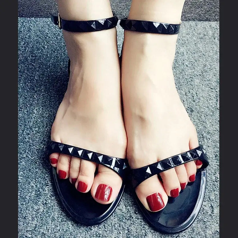 Black studded sandals with red toenails.