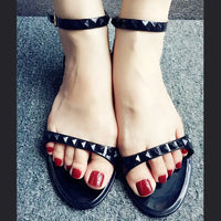 Black studded sandals with red toenails.