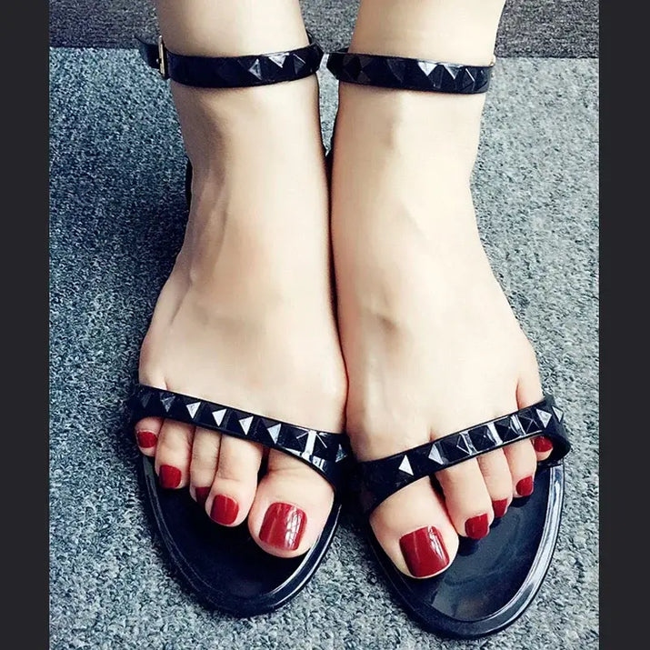 Black studded sandals with red toenails.