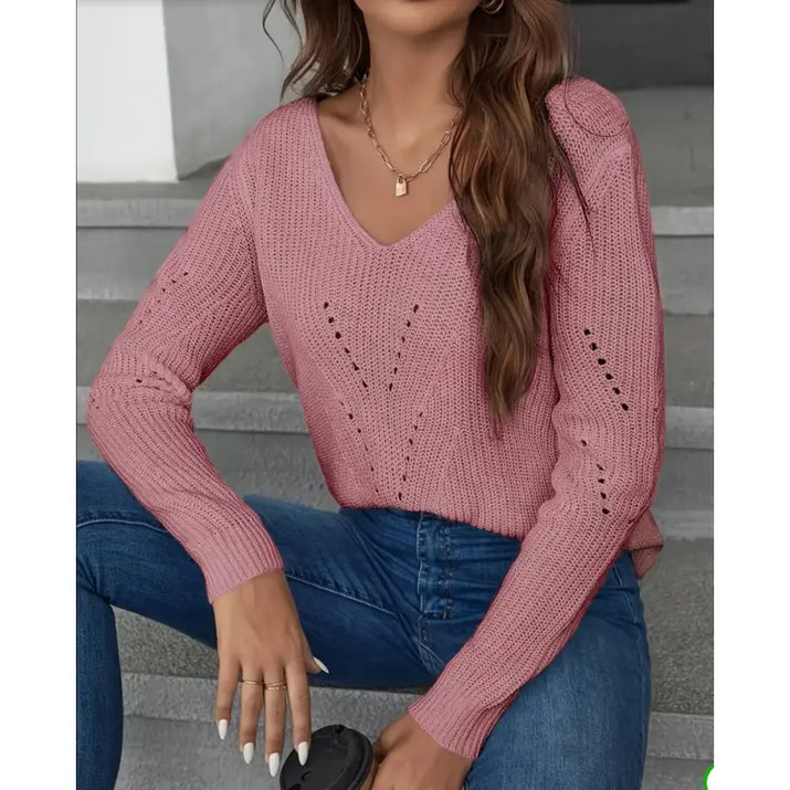 Person wearing a pink knitted sweater and blue jeans sitting on steps.