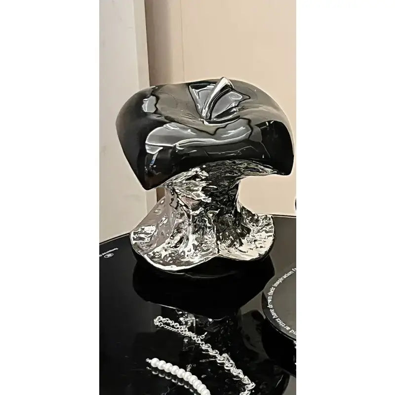 Black and silver decorative object on a reflective surface