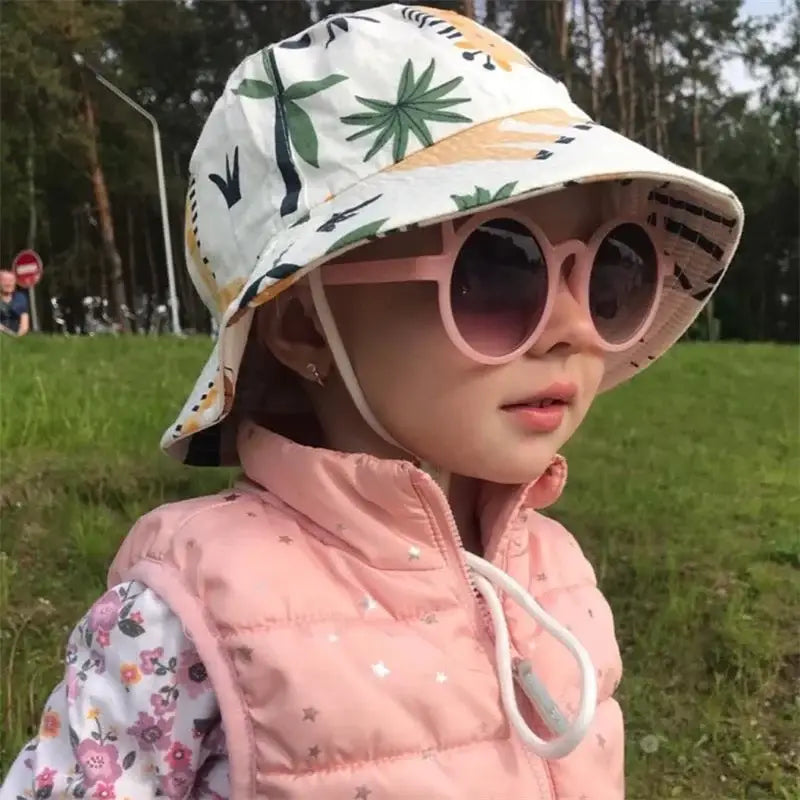 Child wearing a cartoon unisex fisherman hat with pink sunglasses and patterned bucket hat