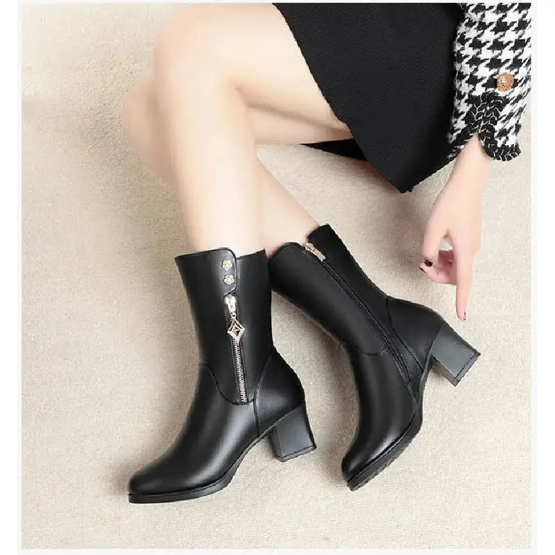 Black leather boots with zippers worn by a person on a beige carpet.