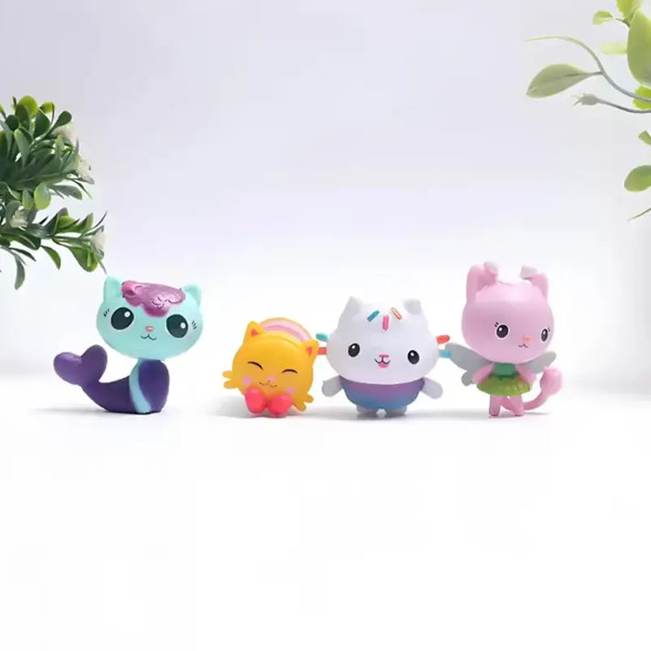 Four colorful cat-shaped figurines on a white background with greenery.