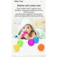 Baby playing with colorful rubber teething balls on a light background