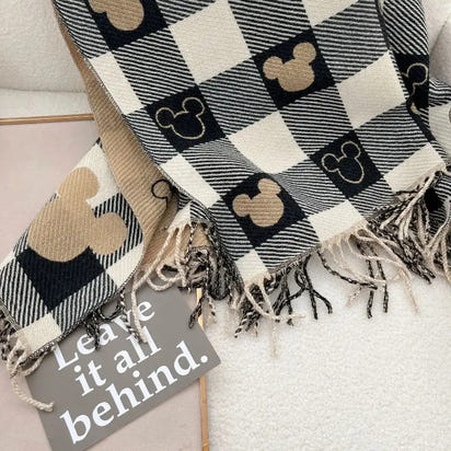Plaid blanket with Mickey Mouse icons and a sign saying 'Leave it all behind' on a light background