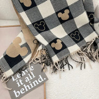 Plaid blanket with Mickey Mouse icons and a sign saying 'Leave it all behind' on a light background