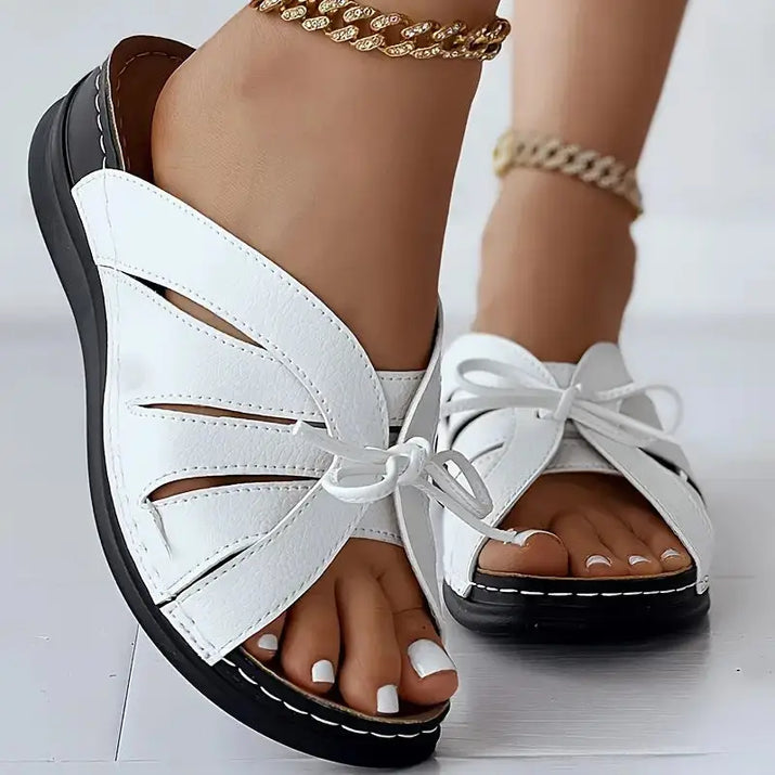 White leather sandals with black soles.