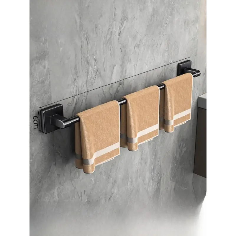 Wall-mounted towel rack with three beige towels.
