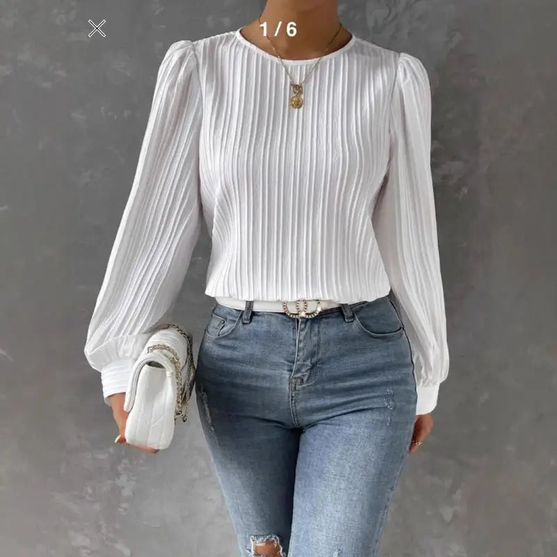 Woman wearing a white pleated blouse and jeans.