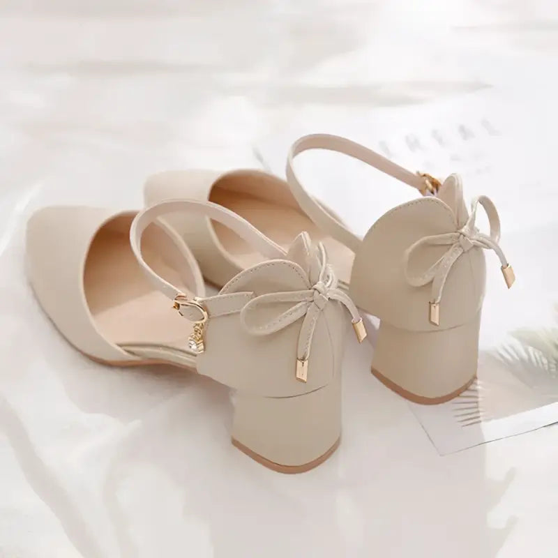 Beige ankle strap heels with bow detail.