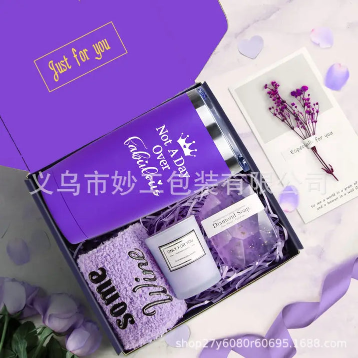 Purple gift box with tumbler, candle, soap, and towel.