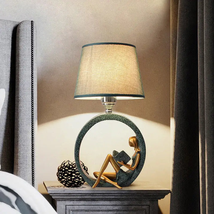 Decorative lamp with reading woman figure.