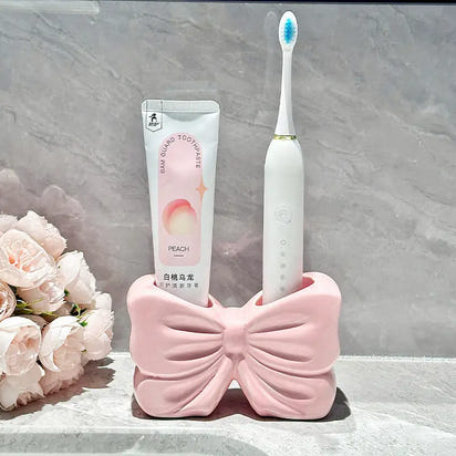 Pink bow-shaped toothbrush and toothpaste holder.