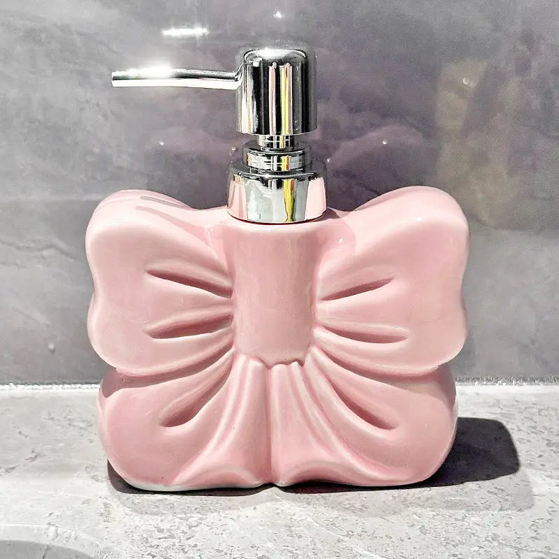 Pink bow-shaped soap dispenser with chrome pump.