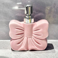 Pink bow-shaped soap dispenser with chrome pump.