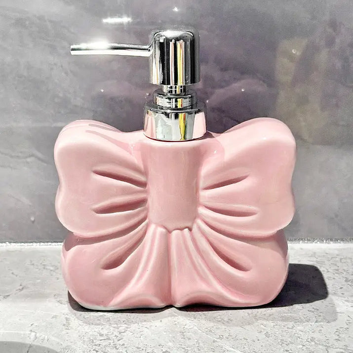 Pink bow-shaped soap dispenser with chrome pump.