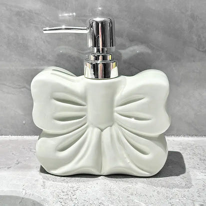 White, bow-shaped soap dispenser with chrome pump.