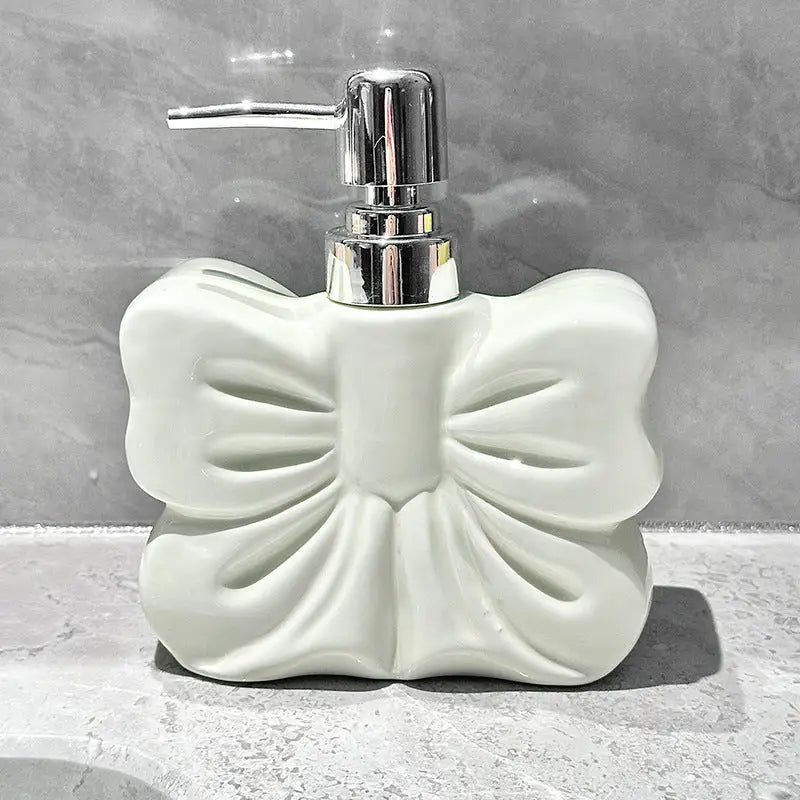 White, bow-shaped soap dispenser with chrome pump.