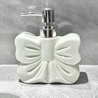 White, bow-shaped soap dispenser with chrome pump.
