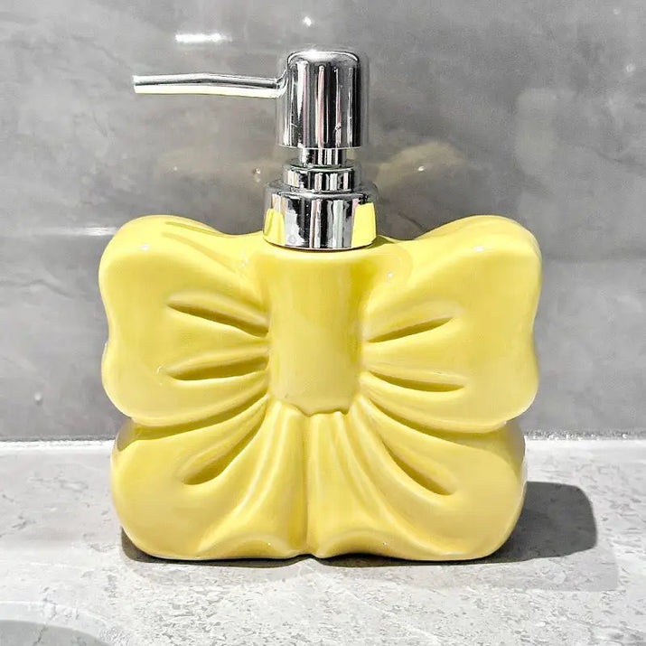 Yellow ceramic soap dispenser with bow design.