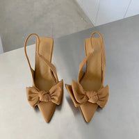 Tan pointed-toe heels with bow detail.