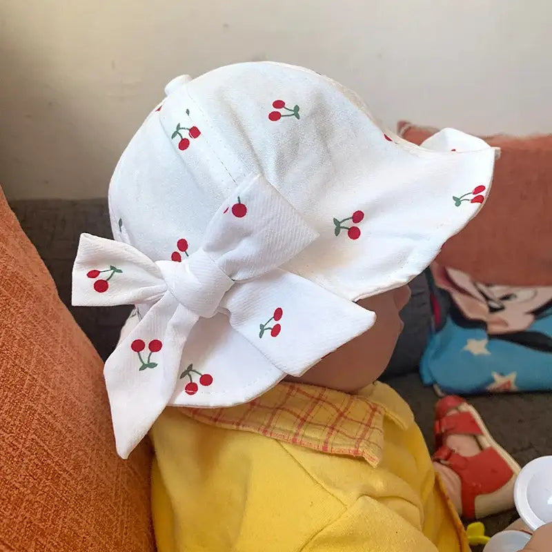 White cherry-patterned baby sun hat with bow.