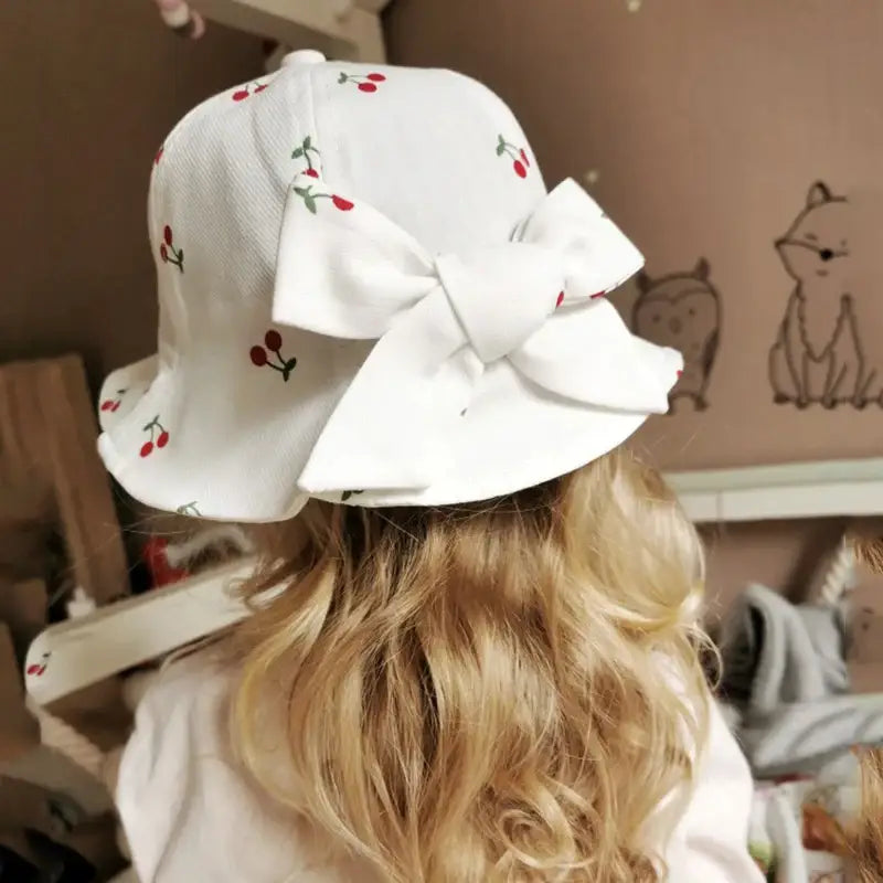 White cherry-patterned sun hat with bow.