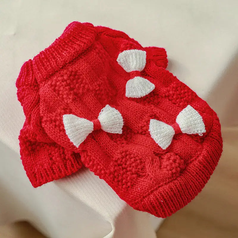 Red knitted dog sweater with white bows.