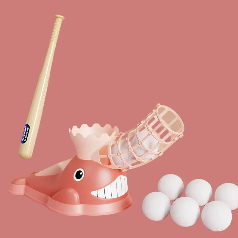 Pink whale-shaped baseball pitching machine with bat and balls.