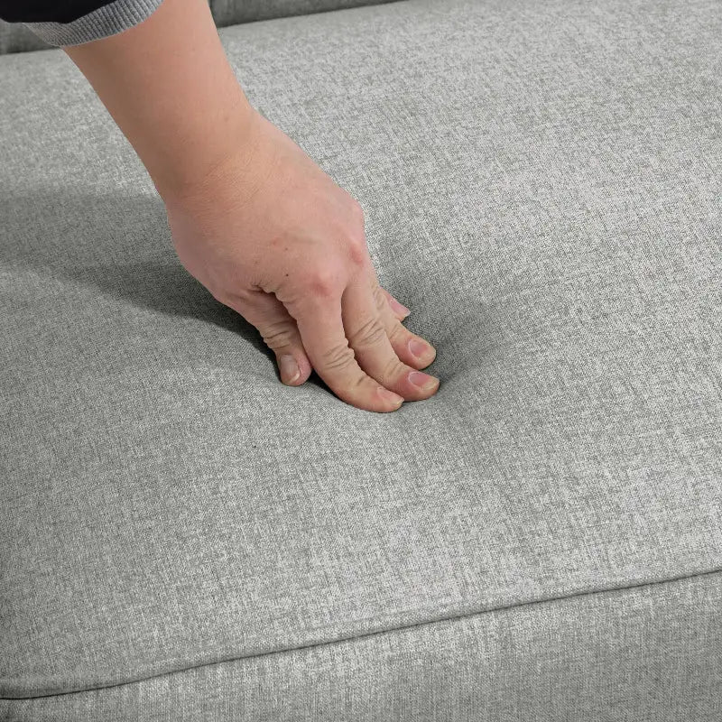 Hand pressing into gray upholstered cushion.