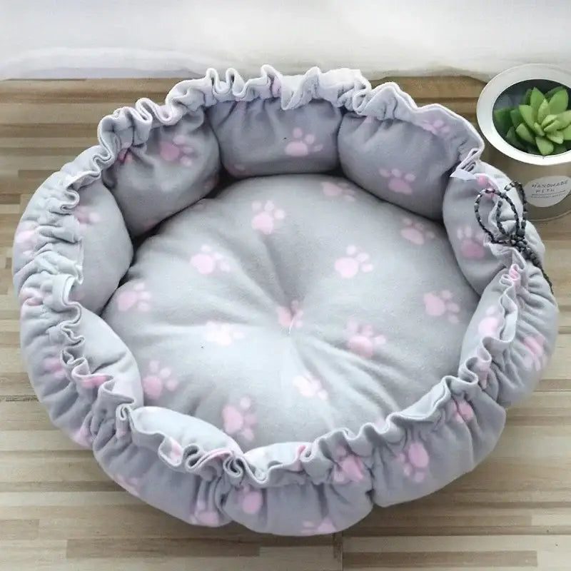 Round, gray pet bed with pink paw prints.