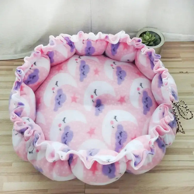 Round pink pet bed with moon pattern.