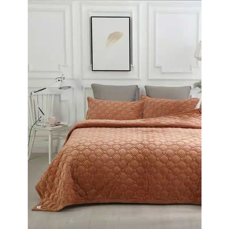 Quilted orange bedspread with matching pillow shams.