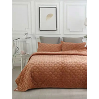 Quilted orange bedspread with matching pillow shams.