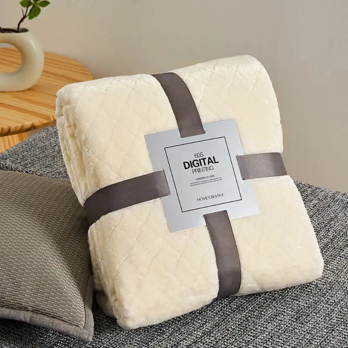 Cream-colored, plush blanket with gray ribbon.