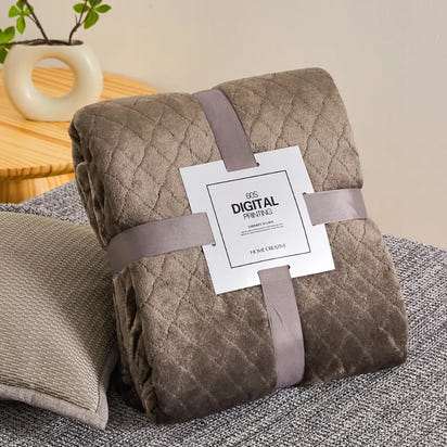 Folded, quilted, brown blanket with ribbon and tag.