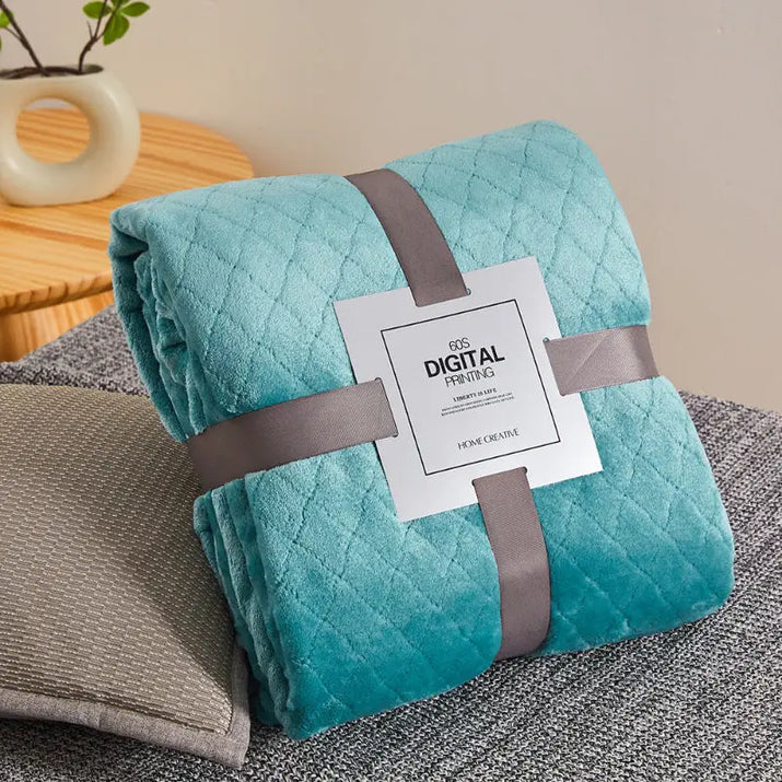Turquoise quilted blanket with gray ribbon.