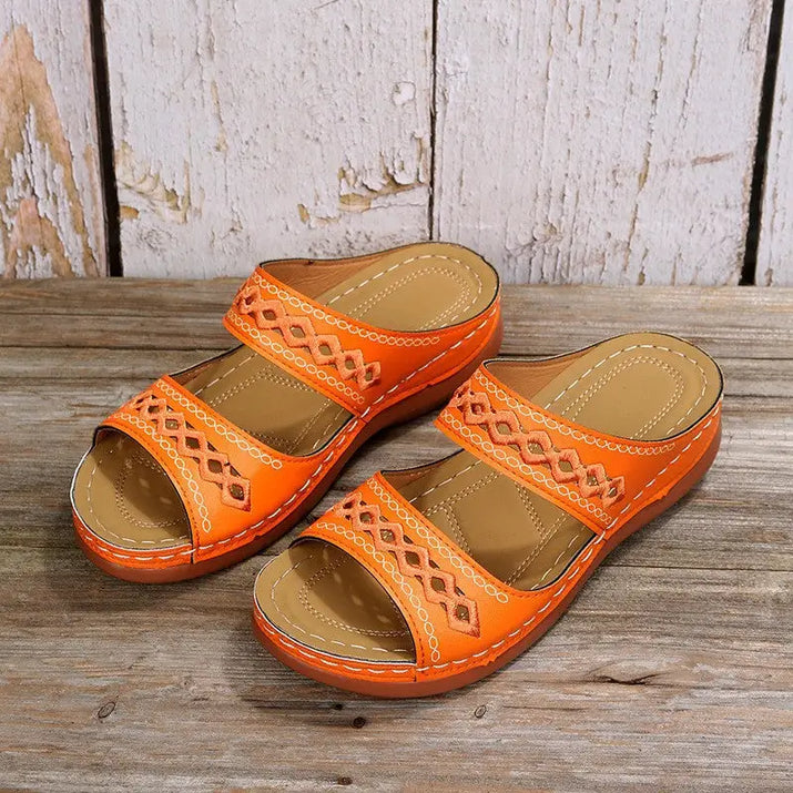 Orange leather sandals with decorative cutouts.
