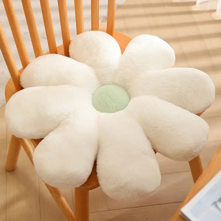 White daisy-shaped plush cushion with a green center.