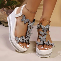 White platform sandals with butterfly embellishments.