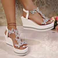 White wedge sandals with butterfly embellishments.