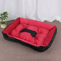 Red and black plush dog bed with bone-shaped cutout.